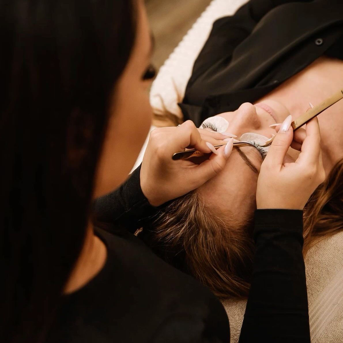 Nancy Gómez aplicando extensiones de pestañas a una clienta en su cabina